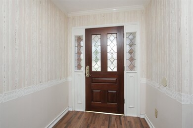 The entry of the home is warm and inviting with wood laminate flooring and a front door with a decorative windows.