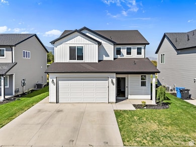 View of front of house featuring board and batten siding, concrete driveway, roof with shingles, and a front yard