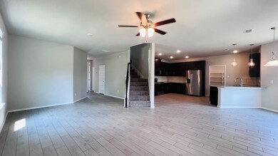 Unfurnished living room with stairs, a ceiling fan, and light wood-style flooring