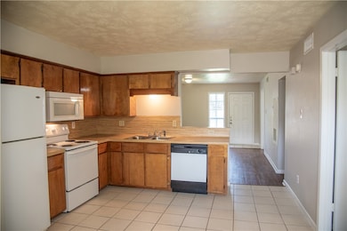 Kitchen featuring white appliances, a sink, light