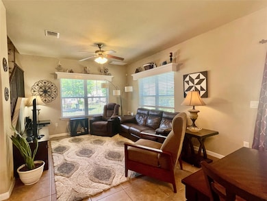 Living room featuring visible vents, ceiling fan,