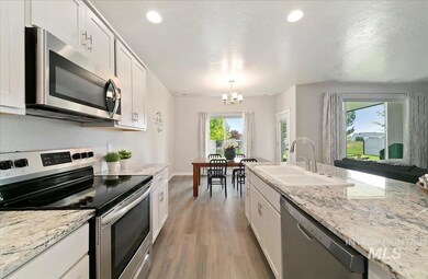 Kitchen with stainless steel appliances, light wood-type flooring, a chandelier, white cabinets, and a textured ceiling