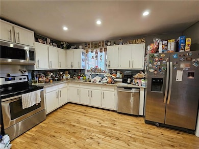 Kitchen with appliances with stainless steel finishes, white cabinetry, light wood-style flooring, recessed lighting, and backsplash