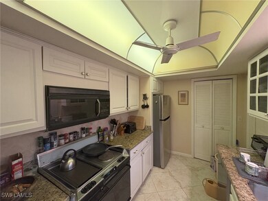 Kitchen with appliances with stainless steel finishes, dark stone countertops, white cabinetry, light tile patterned floors, and a ceiling fan
