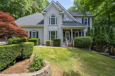 Traditional-style home featuring roof with shingles, stucco siding, a front lawn, and a porch