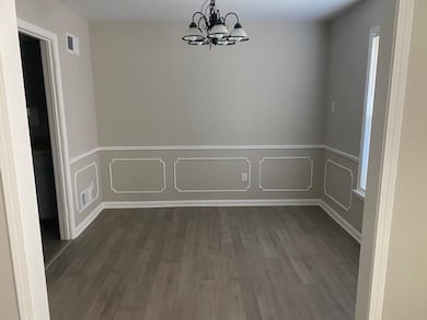 Unfurnished dining area with a chandelier, dark wood-type flooring, wainscoting, and a decorative wall