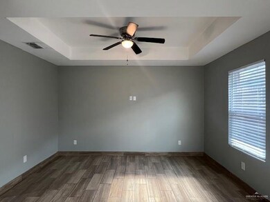 Spare room with ceiling fan, a tray ceiling, and dark hardwood / wood-style floors