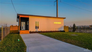 View of front of house with stucco siding, fence, and a front lawn