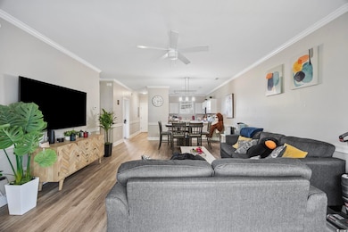 Living room with ornamental molding, wood finished floors, and ceiling fan