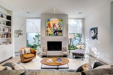 The primary living area surrounds a sleek fireplace, and offers great light from floor to ceiling windows.