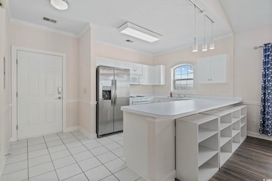 Kitchen featuring white appliances, a peninsula, light countertops, a sink, and white cabinetry