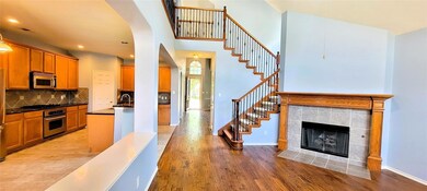 Kitchen with decorative backsplash, light hardwood / wood-style floors, appliances with stainless steel finishes, and a tiled fireplace