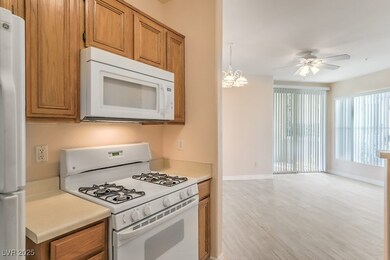 Kitchen with white appliances, light countertops, light wood-type flooring, brown cabinetry, and a chandelier