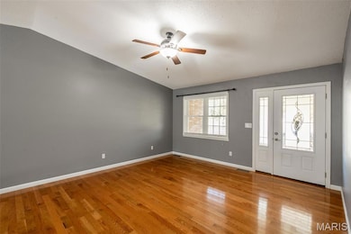 Entryway featuring light wood finished floors, lofted ceiling, ceiling fan, and a textured ceiling