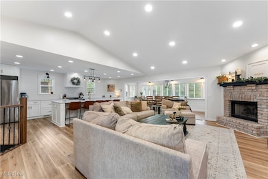 Living area with recessed lighting, vaulted ceiling, light wood-style floors, healthy amount of natural light, and a fireplace