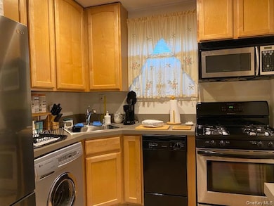Kitchen featuring stainless steel appliances, washer / dryer, light countertops, and light brown cabinetry
