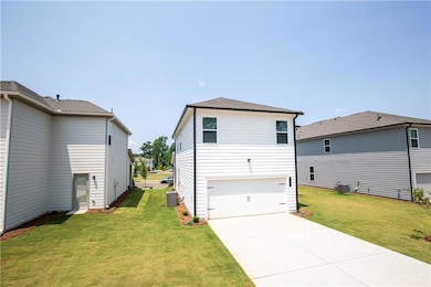 Rear view of house with an attached garage, a yard, and concrete driveway