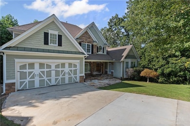 Craftsman-style house with stone siding, concrete driveway, roof with shingles, and a standing seam roof