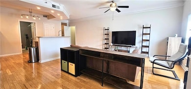 Living area featuring light wood-style flooring, ceiling fan, ornamental molding, and baseboards
