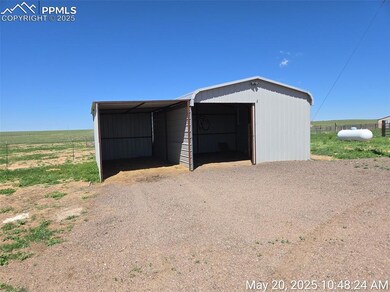 View of pole building with a carport and dirt driveway