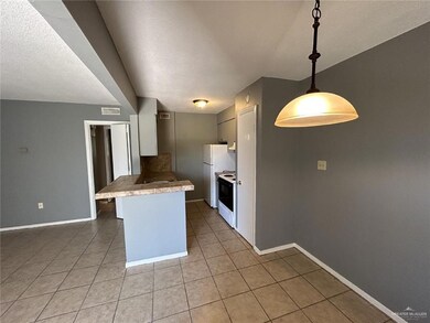 Kitchen featuring a textured ceiling, tile countertops, range with electric stovetop, light tile patterned floors, and baseboards