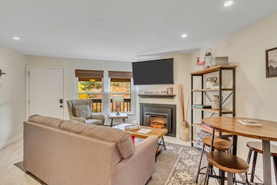 Living room with recessed lighting, a fireplace with flush hearth, and light wood-style flooring