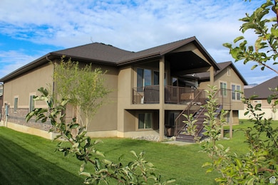 Rear view of property with a lawn, stairs, stucco siding, a patio, and a balcony