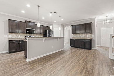 Kitchen with appliances with stainless steel finishes, arched walkways, dark brown cabinets, tasteful backsplash, and recessed lighting