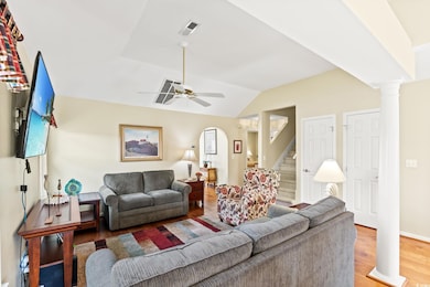 Living room featuring decorative columns, lofted ceiling, stairway, ceiling fan, and wood finished floors