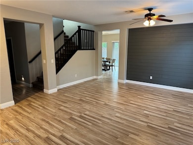 Unfurnished room featuring light wood finished floors, stairway, and ceiling fan