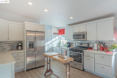 Kitchen featuring decorative backsplash, appliances with stainless steel finishes, light wood finished floors, recessed lighting, and white cabinetry