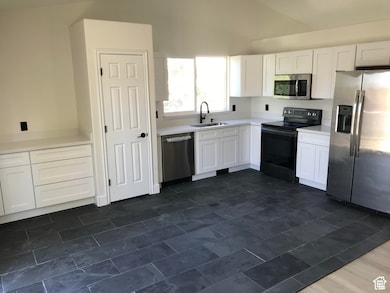 Kitchen featuring white cabinets, stainless steel appliances, and lofted ceiling
