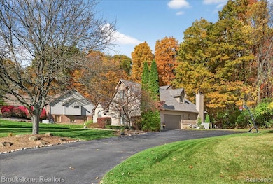 View of front of house featuring a front lawn, a chimney, a garage, and driveway