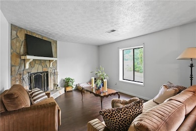 Living area with wood finished floors, a textured ceiling, and a fireplace