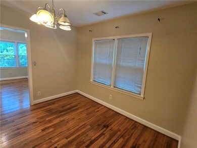 Unfurnished room with a chandelier, wood finished floors, and baseboards