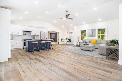 Living area featuring recessed lighting, ceiling fan, light wood-style flooring, and lofted ceiling