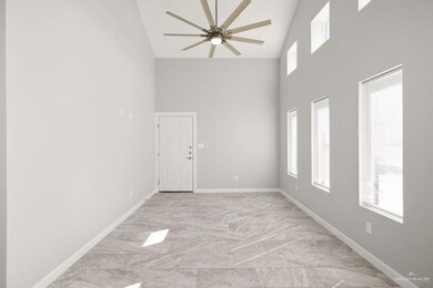 Empty room with ceiling fan, high vaulted ceiling, marble finish floor, and baseboards