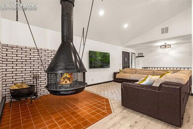 Living area with high vaulted ceiling, wood finished floors, a wood stove, baseboards, and visible vents