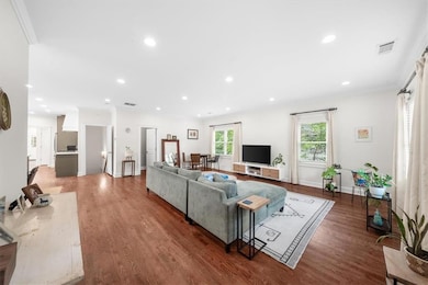 Living area with wood finished floors, recessed lighting, crown molding, and baseboards