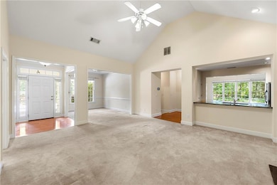 Unfurnished living room with carpet floors, high vaulted ceiling, ceiling fan, baseboards, and a sink