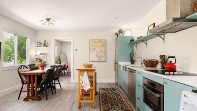 Kitchen featuring open shelves, blue cabinetry, wall chimney range hood, and stainless steel appliances
