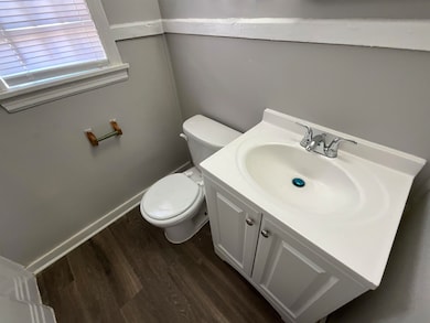 Bathroom with toilet, baseboards, wood finished fl