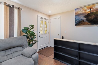 Living area featuring dark wood-type flooring, a textured ceiling, and recessed lighting
