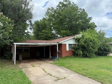 View of front of home with driveway, an attached carport, a front lawn, and brick siding