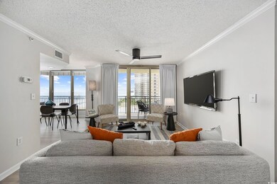 Living room with ceiling fan, crown molding, a textured ceiling, and expansive windows