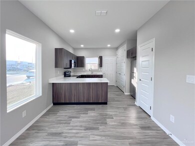 Kitchen with a sink, a peninsula, appliances with stainless steel finishes, light countertops, and recessed lighting