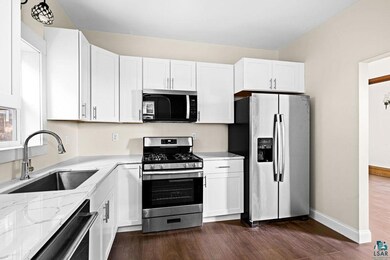Kitchen with dark wood-type flooring, sink, light 
