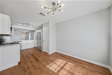 Kitchen with white cabinetry, light countertops, a chandelier, appliances with stainless steel finishes, and dark wood-style floors