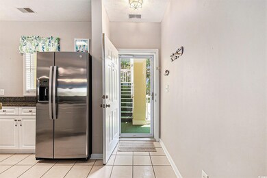 Kitchen featuring stainless steel refrigerator with ice dispenser, light tile patterned flooring, baseboards, and white cabinetry