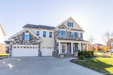 View of front of home featuring stone siding, covered porch, an attached garage, concrete driveway, and a front lawn